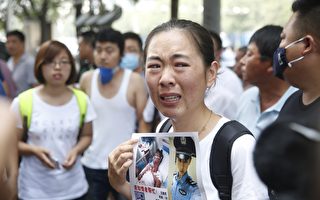 2015年8月16日，天津，新闻发布会的会场外，一名失踪的消防员家属神情悲伤。(STR/AFP/Getty Images)
