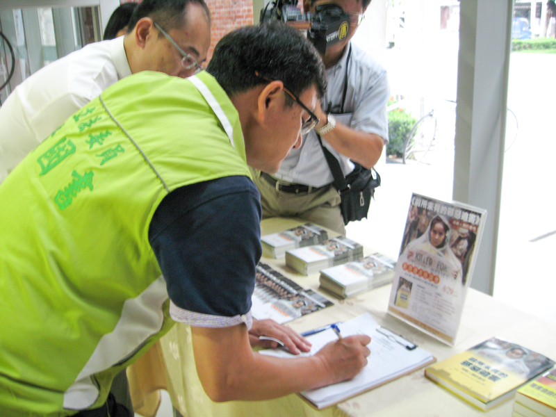 立委黃國書正在「刑事舉報江澤民」聯署書上簽名。(明慧網)