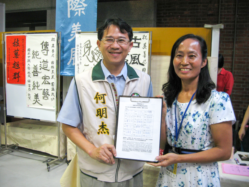台中市議員何明杰(左)展示了他所簽署的「刑事舉報江澤民」聯署書。(明慧網)