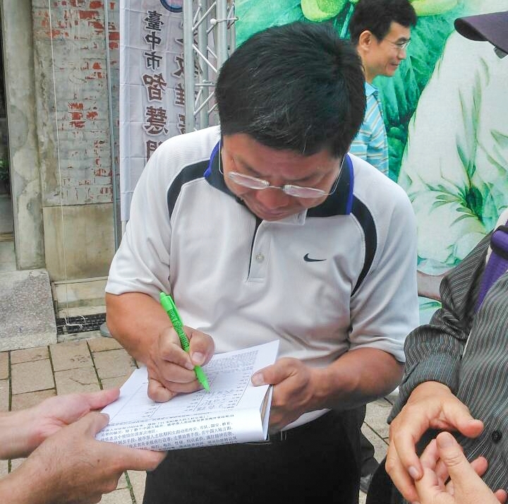 台中市文化局副局長施純福正在「刑事舉報江澤民」聯署書上簽名。(明慧網)