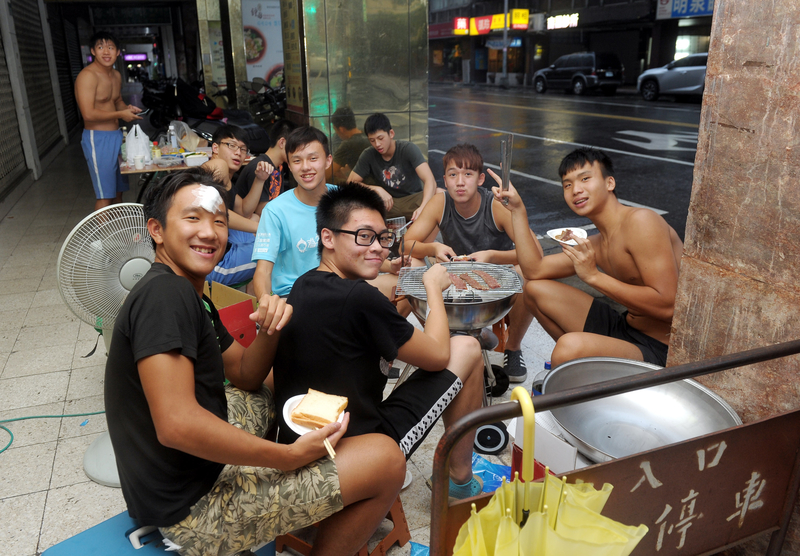 中央氣象局27日發布強烈颱風杜鵑陸上颱風警報,下午起即雨勢不斷,適逢中秋節,台北一群年輕人窩在騎樓內,無懼風雨來襲仍然圍坐烤肉聯誼。(中央社)