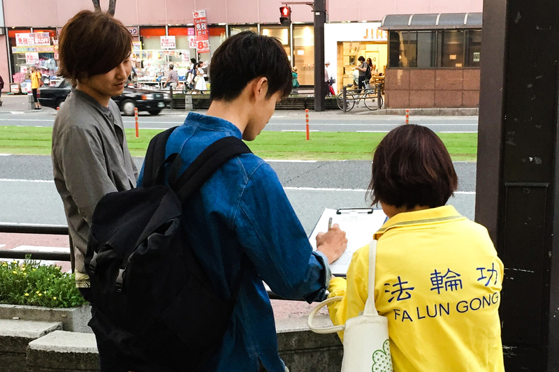 日本各地的法輪功學員在街頭向日本民眾講述法輪功受迫害的真相,聲援控江。圖為日本熊本縣的法輪功學員在街頭聯署舉報的情景。(大紀元圖片)