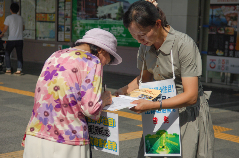 日本各地的法輪功學員在街頭向日本民眾講述法輪功受迫害的真相,聲援控告江澤民的簽名。圖為日本大阪的法輪功學員在街頭聯署舉報江澤民的情景。(大紀元圖片)