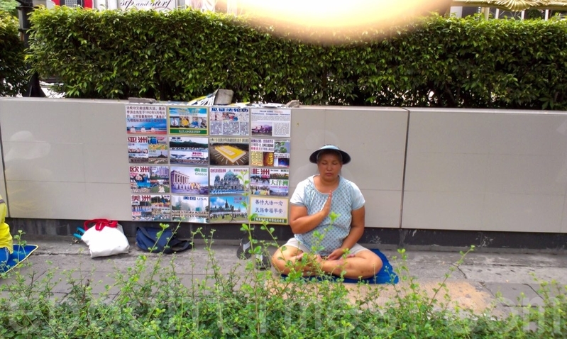 大陸法輪功學員尹麗萍在中共江澤民集團發動這場迫害中,先後被7次綁架、3次勞教、六次因迫害生命奄奄一息被抬回家,但每次她都奇蹟般的活了過來。她帶著要在國際法庭控告江澤民的心願,輾轉流亡海外。圖為放展板向大陸遊客講真相(大紀元資料室)