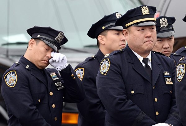 2015年1月4日，殉职纽约华裔警察刘文健的葬礼中，一位同僚悲伤的落泪。(JEWEL SAMAD/AFP)