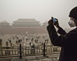 北京从11月27日起开始遭遇严重污染；11月30日，污染指数惊人，PM2.5（微细悬浮粒子）浓度最高接近1,000微克/立方米。这个浓度逼近造成逾万人死亡的1952年伦敦烟雾事件之污染浓度。图为一位戴着口罩的民众正在拍照。(Kevin Frayer/Getty Images)