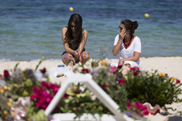 2015年6月28日，突尼斯苏塞市的一家酒店遭遇武装袭击，二位幸存的旅客悼念罹难者。（KENZO TRIBOUILLARD/AFP）