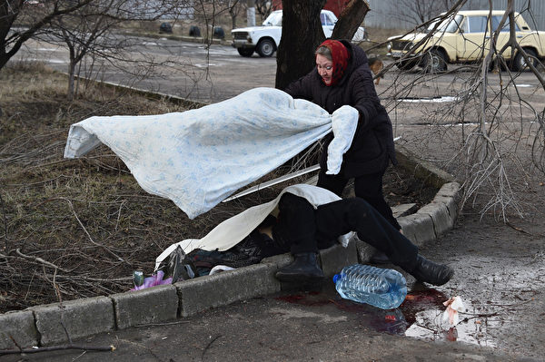 2015年2月4日，乌克兰顿涅茨克，乌克兰东部战事持续，一名女子为街边的罹难者盖上白布。(DOMINIQUE FAGET/AFP)
