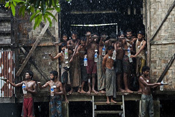 2015年6月4日，缅甸若开邦，被救的移民在大雨中用矿泉水瓶取水。 (Ye Aung Thu/AFP/Getty Images)