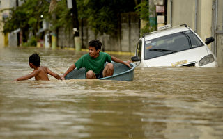 茉莉颱風（Melor）肆虐菲律賓，首都馬尼拉附近有數萬民眾今天在水深及腰的農地跋涉，然而另1個風暴恐將帶來更多雨量。圖為12月18日，兩個孩子用大盆當船在水中划。(NOEL CELIS/AFP/Getty Images)
