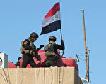 2015年12月28日，伊拉克精銳部隊12月28日收復安巴爾省首府拉馬迪後，在中央政府大樓樓頂重新升起伊拉克國旗。（AHMAD AL-RUBAYE/AFP/Getty Images）