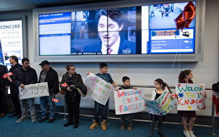 去年12月28日温哥华国际机场，库尔迪（Kurdi）家人在机场迎接他们的叙利亚难民亲属，电视上在播放特鲁多致词欢迎叙难民。（加通社）