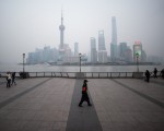 2016年1月18日，中國上海，一名保安走在橫跨浦東新區金融區的黃浦江外灘。(JOHANNES EISELE/AFP)
