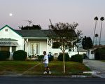 A man waters the lawn and sidewalk in front of his house beneath an almost full moon during the early evening in Monterey Park, Los Angeles County, on January 14, 2014 in California, where the median price of a home in Los Angeles County jumped by 22.2 percent in December, compared with the same month a year ago, while the number of homes sold dipped by 13.3 percent, a real estate information service announced today.  The median price for a Southern California home was $395,000 in December, up 22.3 percent from the same period last year and highest since February 2008, when the median was $408,000, according to DataQuick. The Cancer Full Moon occurs on January 15-16. AFP PHOTO/Frederic J. BROWN        (Photo credit should read FREDERIC J. BROWN/AFP/Getty Images)