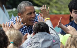 3月28日，美国总统奥巴马在一年一度的白宫复活节滚彩蛋活动中与儿童们拍手互动。 
 （NICHOLAS KAMM/AFP/Getty Images)