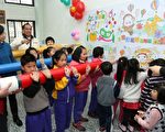 三星乡立幼儿园学童一起扛着2米长彩色铅笔，象征如椽之笔画出童趣梦想。（曾汉东／大纪元）