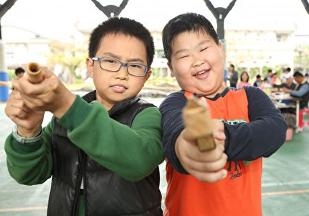 大湖国小四年级学生陈柏任(左)玩“拉泡泡”、张纮綮玩“木枪”。(曾汉东/大纪元)