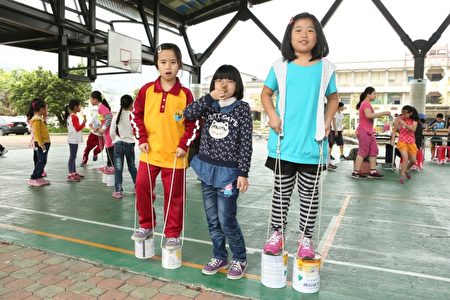 大湖国小四年级学生江旻(右)、吕伊晴玩铁罐踩高跷。(曾汉东/大纪元)