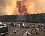 2016年5月3日，阿尔伯塔省农林厅提供的照片显示，麦克默里堡市的浓烟。大火横扫油砂区，导致艾伯塔省进行了有史以来最大的疏散。
火势增长迅速，阿尔伯塔省紧急服务署要求麦克默里堡所有居民必须强制疏散。（AFP PHOTO / Lynn Daina）