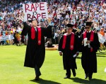 史丹佛大學畢業生以所謂「趣味步行」奇裝異服方式進入典禮會場，圖中學生保羅·哈里森高舉「強暴就是強暴」標語抗議近日的性侵案輕判事件。(PGABRIELLE LURIE/AFP/Getty Images)