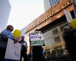 图为2011年10月，抗议华尔街者在洛杉矶市内一家富国银行分行前举牌，牌上写道：为160年的贪婪史庆生。（David McNew/Getty Images）