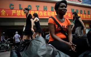 2013年8月26日，来自赞比亚的一名商人坐在廣州一个服装批发市场之外。     (STR/AFP/Getty Images)