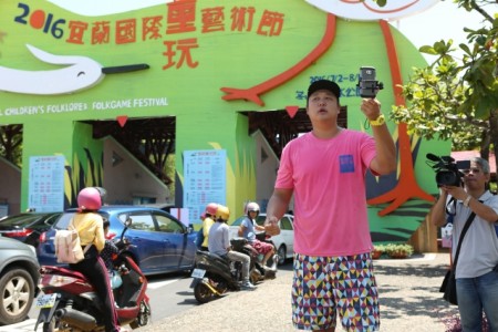 外景主持人哈孝远在宜兰玩童主入口处,以手机现场直播方式为这次优惠讯息曝光。(曾汉东/大纪元)