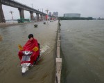 2016年7月2日，一名男子騎摩托車經過被洪水淹沒的大橋。(STR/AFP/Getty Images)