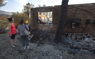 自「沙火」（Sand fire）爆發以來﹐消防部門的滅火費用估計已達2800萬美元。圖為7月25日居民查看被燒毀的家園.。（David McNew/Getty Images）
