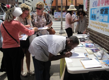 許多過往集會現場的費城居民紛紛了解真相，並在「反強制活摘器官」征簽表上簽名。（李凱西/大紀元）