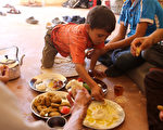 敘利亞達拉雅市遭政府空襲、圍城4年，人民生活艱困，常處於飢餓狀態。敘利亞政府與反抗軍近日達成停火協議，民眾撤離達拉雅後，終於有飯可吃。（AFP PHOTO / Youssef KARWASHAN）