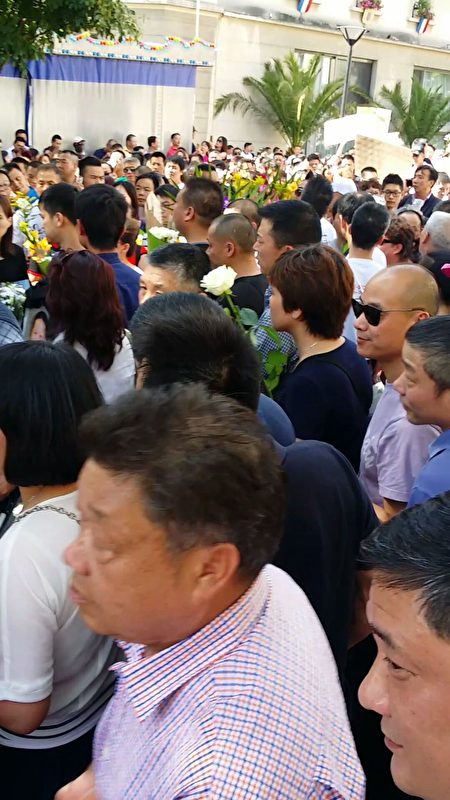 人們懷著憤怒、悲痛與無奈的心情,手捧白色菊花陪著受害者家屬。(解空/大紀元)