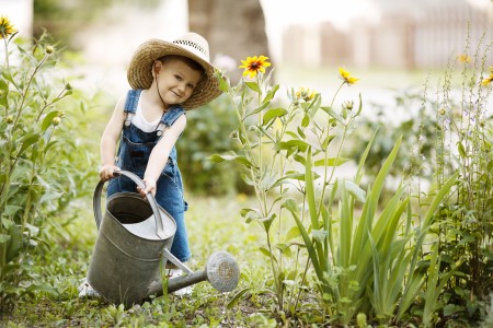 cute little boy with watering can in summer park