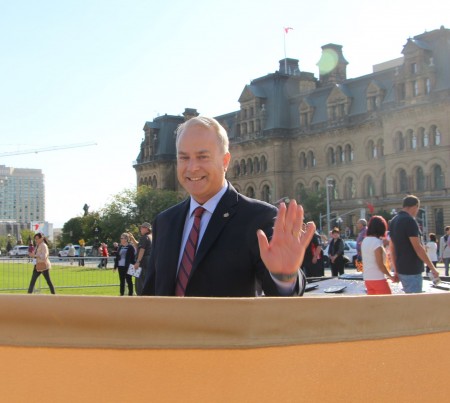 國會議員Kelly Mccauley來到法輪功學員煉功場地,向學員們揮手致意。(大紀元)