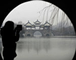 This picture taken on December 26, 2012 shows a woman taking a picture in the snow in Yangzhou, east China's Jiangsu province. A fresh cold snap is hitting most parts of China recently, according to the National Meteorological Center's forecast on December 26.    CHINA OUT   AFP PHOTO        (Photo credit should read STR/AFP/Getty Images)