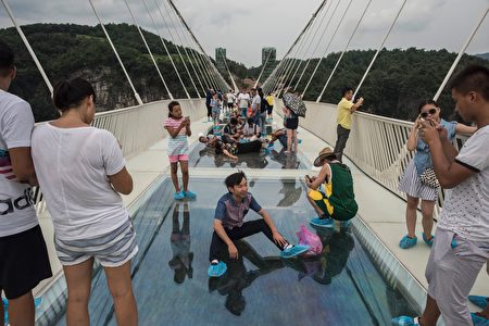 A tourist poses for a photograph on the world's highest and longest glass-bottomed bridge above a valley in Zhangjiajie in China's Hunan Province on August 20, 2016. / AFP / FRED DUFOUR (Photo credit should read FRED DUFOUR/AFP/Getty Images)