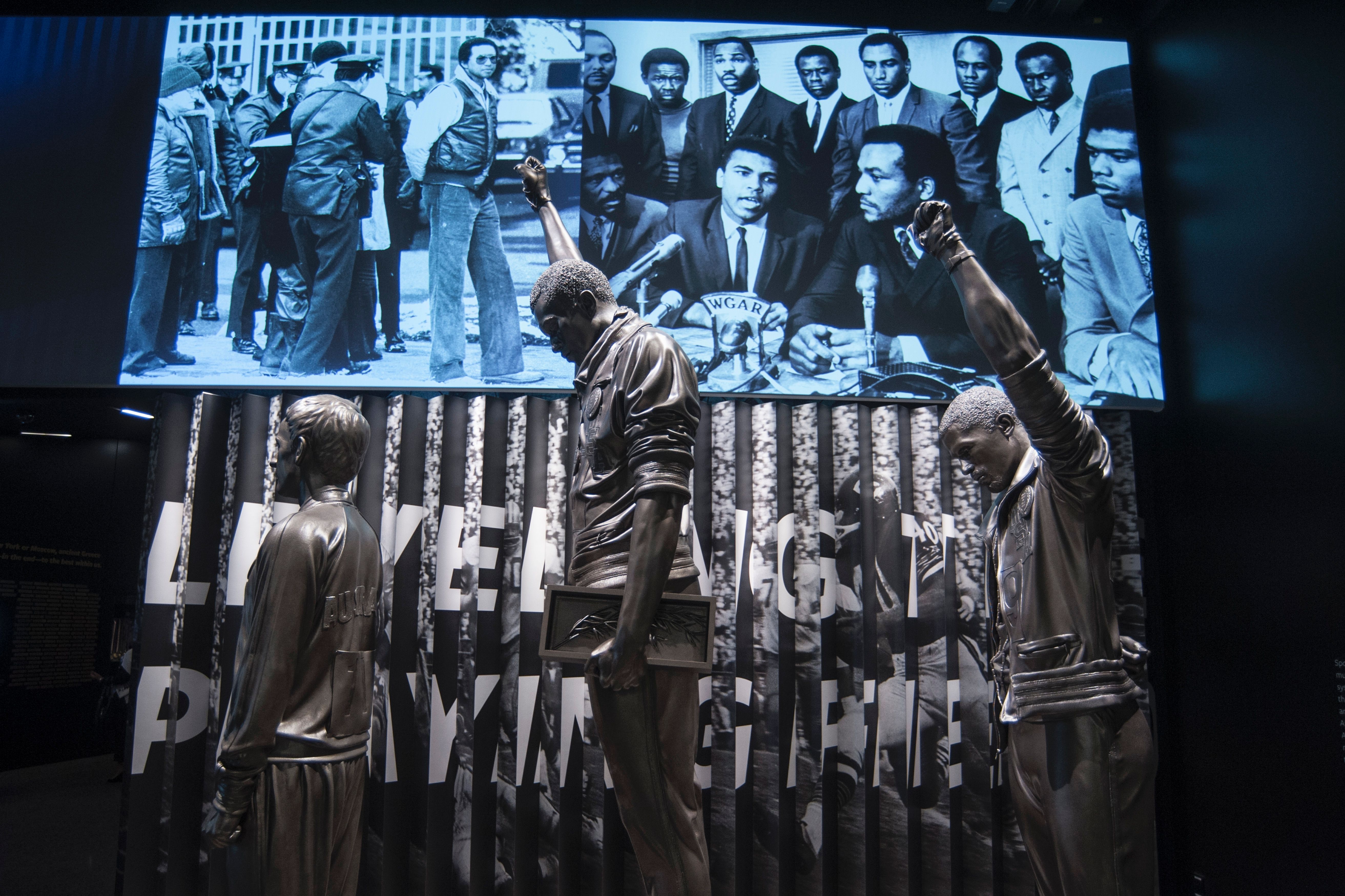 圖中的雕像記錄了1968年墨西哥城奧運會，200米金牌得主Tommie Smith, C,和銅牌得主John Carlos, R,獎台上舉起戴着黑手套的拳頭，並在美國國旗升起時低頭，以抗議美國的種族政策。(PRESTON KERES/AFP/Getty Images)