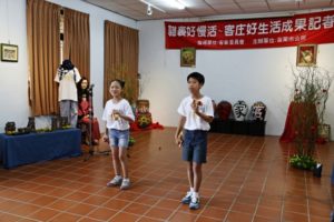 客语口说儿童练功房的学童,用逗趣打竹荚欢迎乡亲来坐。(苗市公所/提供)