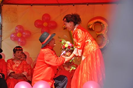 78歲村長新郎莊明洲特別興奮,很大方的在台上向老伴邱紅甘求婚,還大方親吻新娘,博得現場掌聲喝采。(詹亦菱/大紀元)