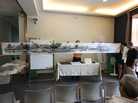 林勳諒老師在美學講座上，展示他的巨幅創作《桂林漓江遊》。（蔡上海／大紀元）