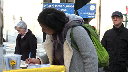 比利時民眾支持法輪功，在制止中共迫害法輪功的請願信上簽字 。（新唐人）