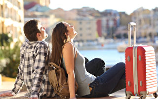 兩個遊人的側視圖有手提箱坐的放鬆和享受在五顏六色的散步的假期。 旅遊概念（fotolia）