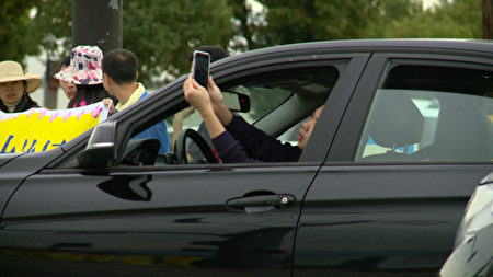洛杉磯法輪功學員拉起的橫幅吸引洛杉磯民眾的注意，開車的民眾趁著紅燈停車時，趕快拍照下來。(劉寧／大紀元)