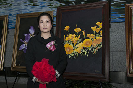 2月7日，華裔畫家王小燕「花之魂」油畫展在舊金山州府大樓開展，圖為王小燕在加州州花旁。（周鳳臨／大紀元）