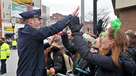 穿戴著翡翠綠服飾、佩帶著三葉苜蓿的當地居民和遊客，觀看波士頓聖派翠克節遊行。（貝拉/大紀元）