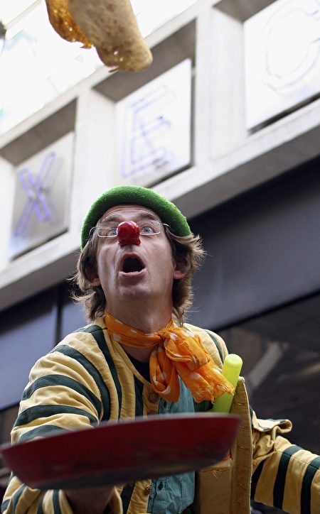 LONDON, ENGLAND - FEBRUARY 28: A contestant dressed as a clown takes part in the annual pancake race in Spitalfields Market, February 28, 2006 in London, England. Participants are expected to don costumes and race a short sprint tossing a pancake as they go to celebrate Shrove Tuesday. (Photo by Marta Travesset/Getty Images)