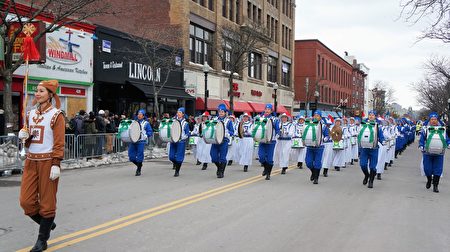 波士頓聖派翠克節遊行隊伍中，身著藍白相間中國傳統服裝的160名樂團成員，手舉「法輪大法」橫幅，方陣整齊，氣勢雄壯。（貝拉/大紀元）