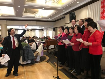 大紐約客家會新春聯歡會，會員們大合唱《客家本色》、《挑擔歌》和《老山歌組曲》，范增昌副會長指揮。