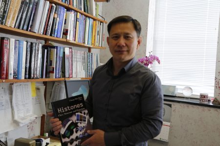 CUNY史坦頓分校華裔生物學教授沈昌輝在辦公室，手拿自己的第一步專業著作。