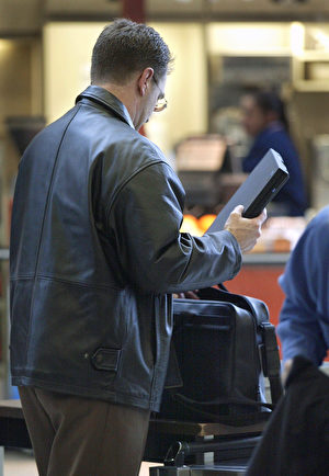 一名旅客在機場安檢後將筆電放入手提行李。(Tim Boyle/Getty Images)